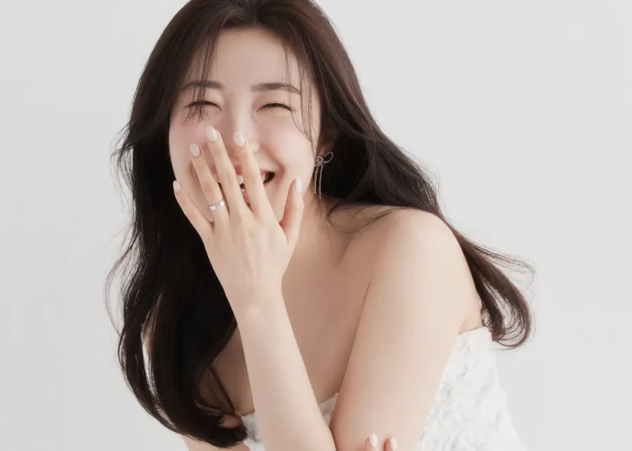 A woman laughing with her hand raised to her face.